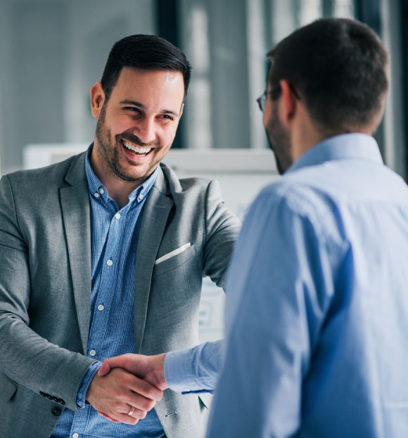 Two businesspeople smiling as they shake hands at a meeting.